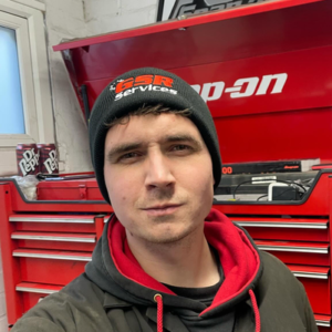 a man taking a selfie in front of a toolbox with a logo hat